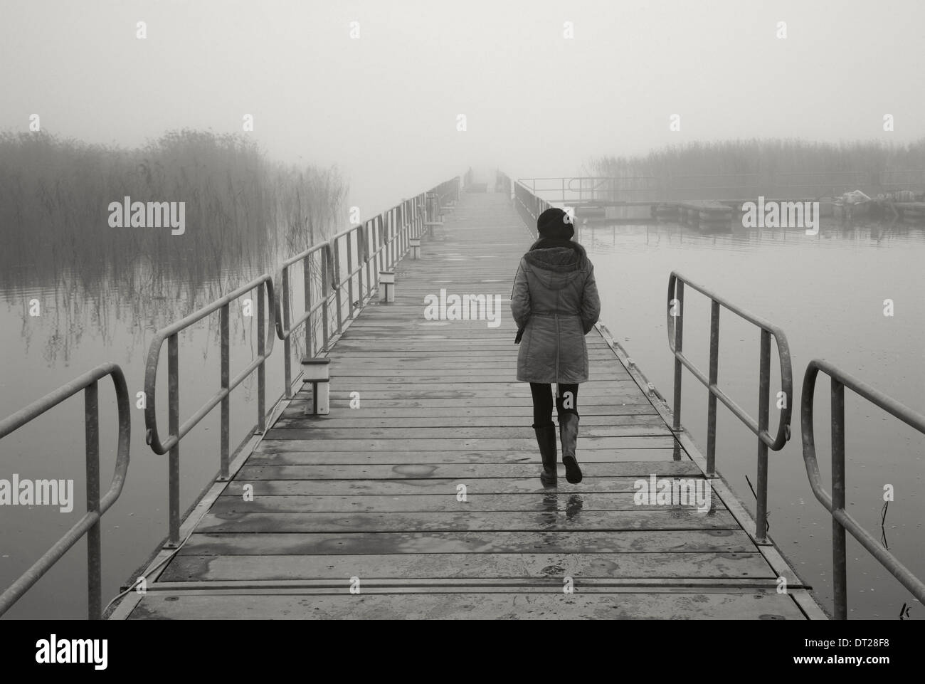 Einsame Frau, die zu Fuß die schwimmenden Fußgänger Brücke von Agios Achilleios Inselchen, Mikri Prespa-See, Florina, Mazedonien, Griechenland Stockfoto