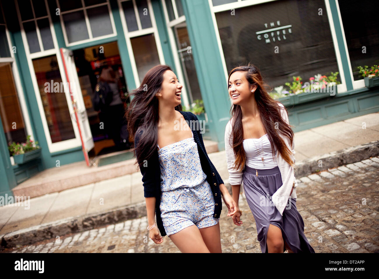 Zwei Mädchen im Teenageralter zu Fuß über Straße, Café im Hintergrund Stockfoto