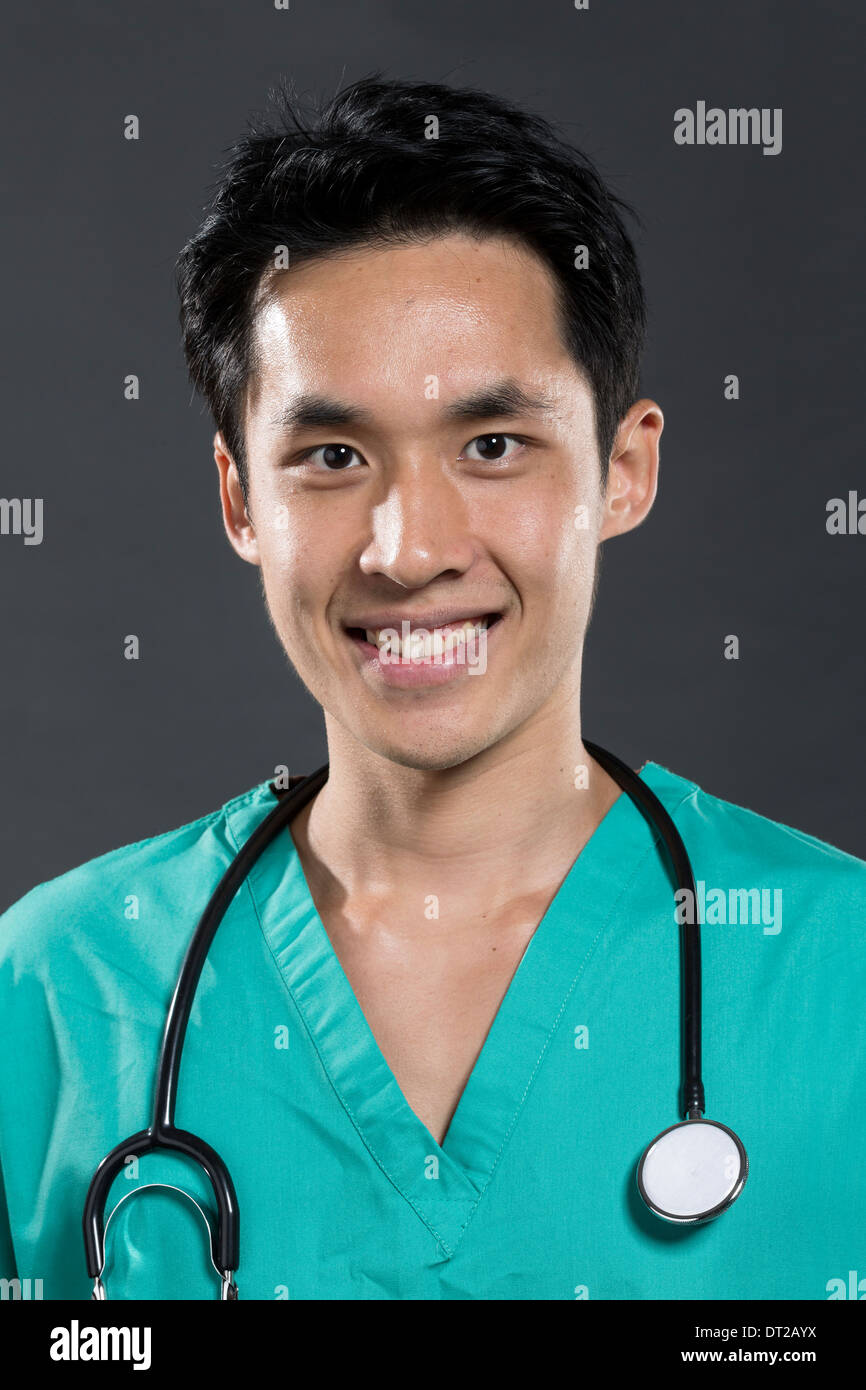 Porträt eines männlichen asiatischen Arzt tragen grün Scrubs. Dunkel grau hinterlegt. Stockfoto