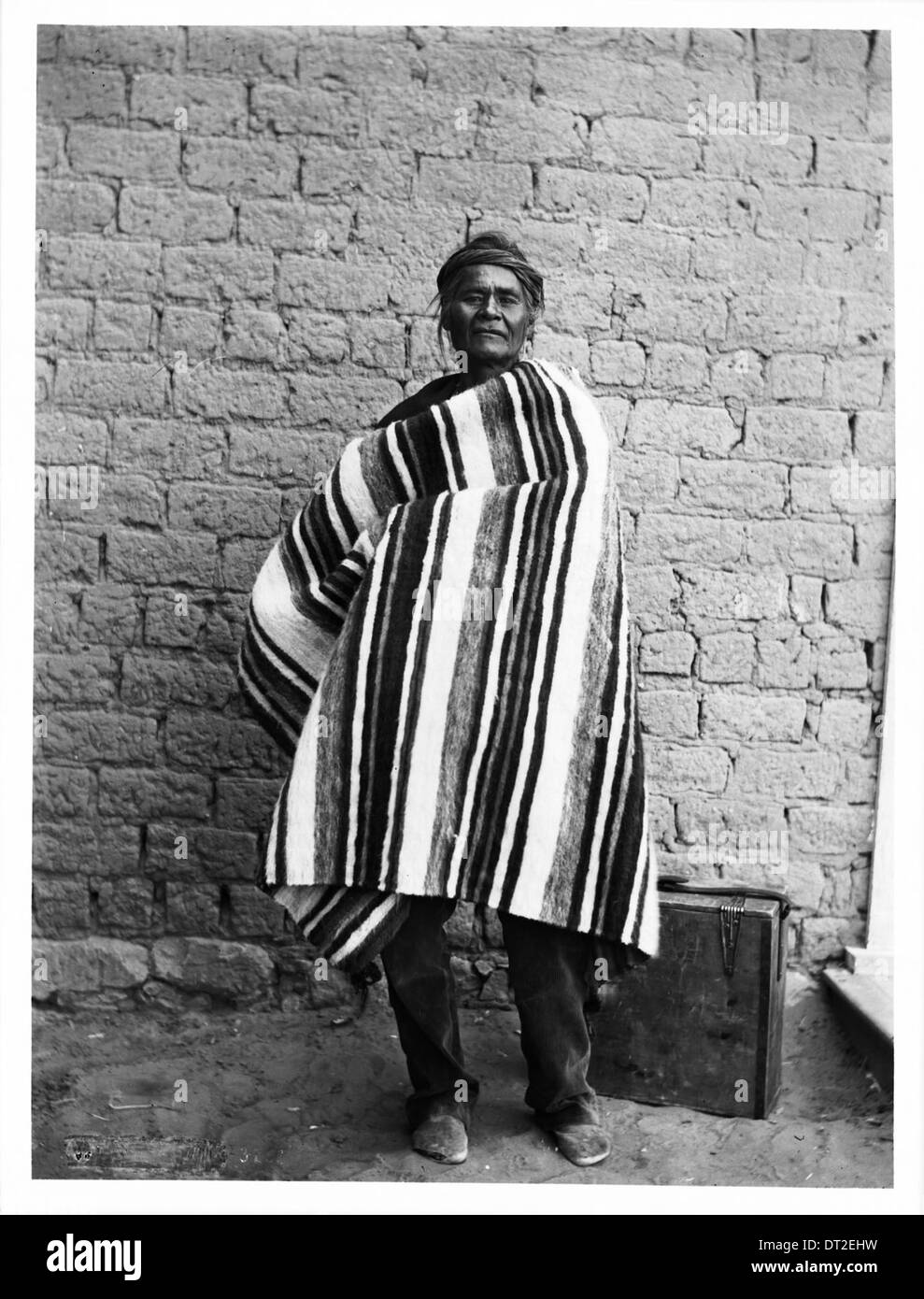 Dieses Foto zeigt einen Navajo-Indianerhäuptling, der mit einem Koffer zu seinen Füßen steht, aufgenommen um 1900. Das Bild zeigt eine wichtige Figur der amerikanischen Ureinwohner der Zeit. Stockfoto