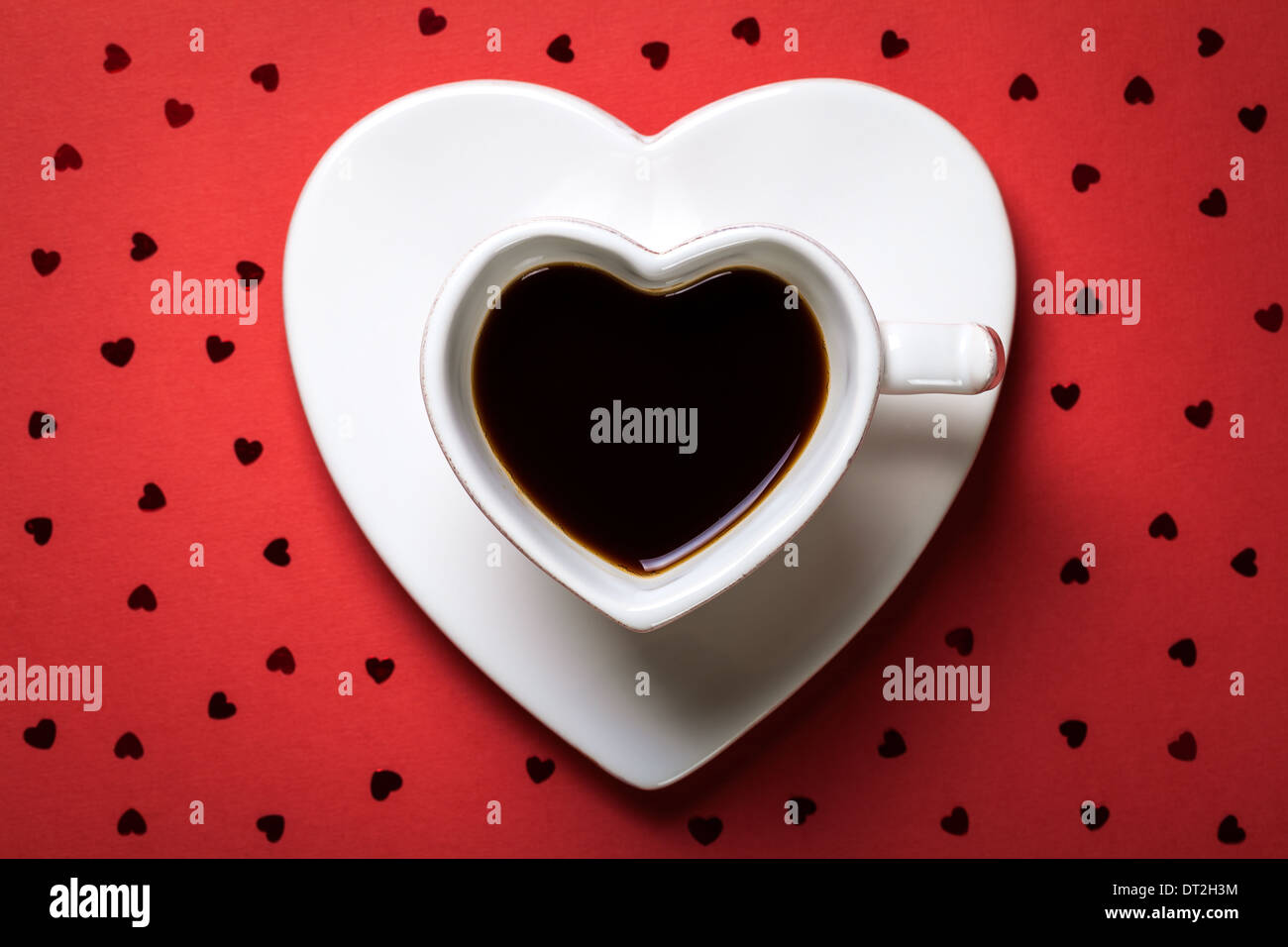 Kaffeetasse in Form des Herzens auf rotem Papierhintergrund. Ansicht von oben Stockfoto