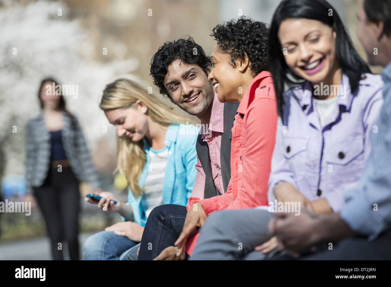 Fünf Leute sitzen in einer Reihe im park Stockfoto