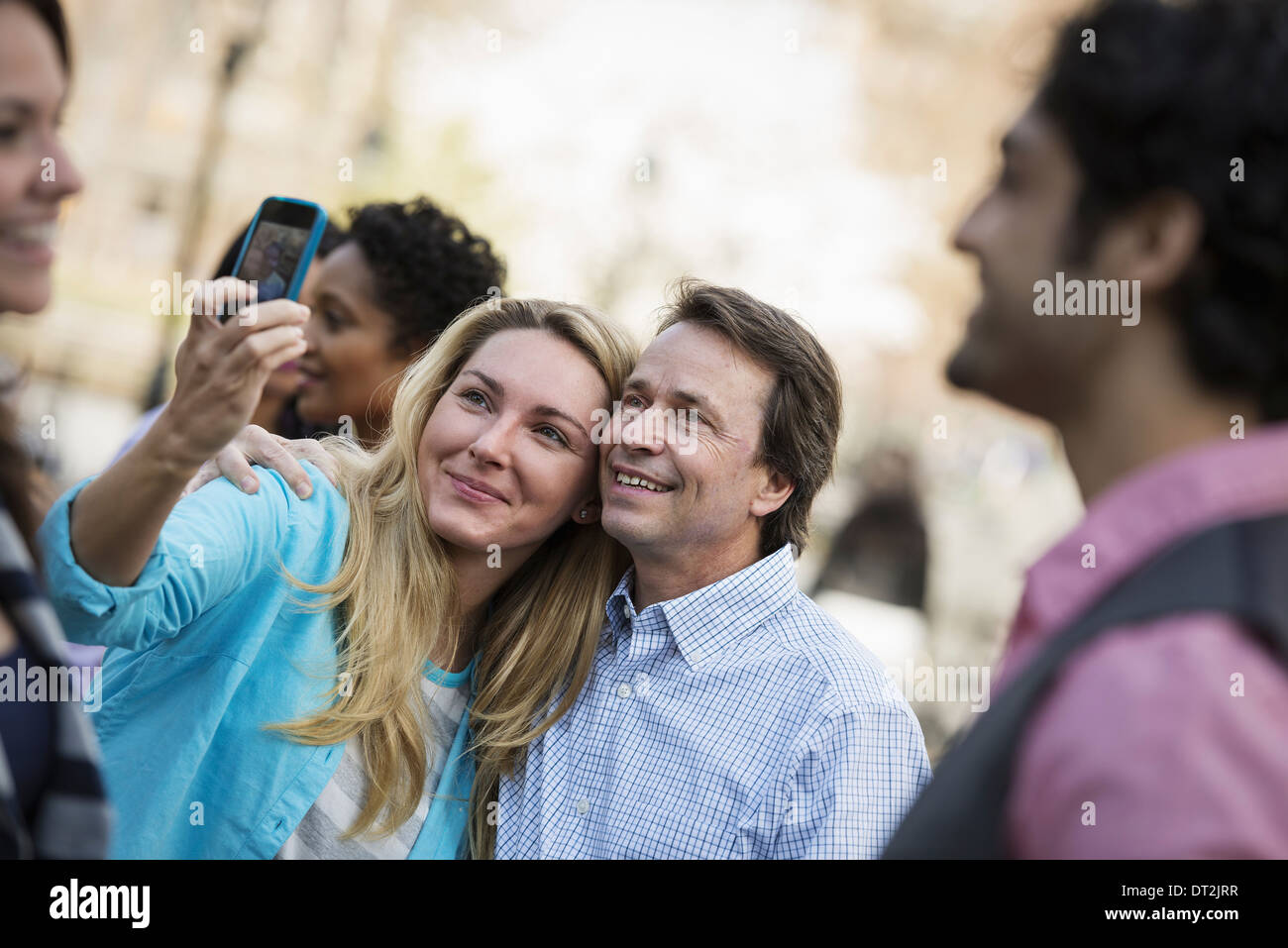 Menschen im Freien in der Stadt im Frühjahr Mal eine Frau mit ihrem Handy eine Foto A Gruppe von Freunden Männernund Frauen nehmen Stockfoto