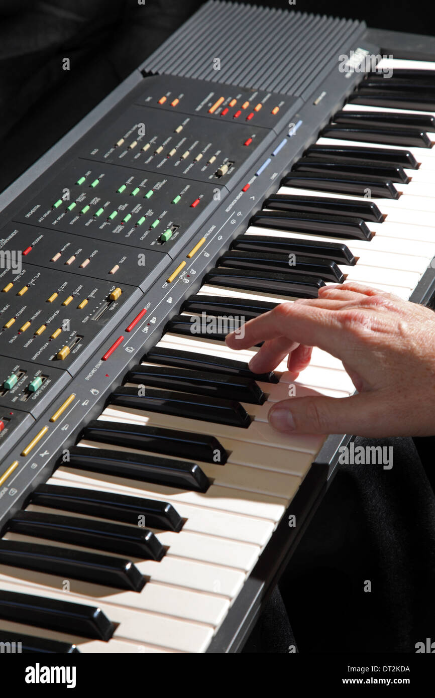 Eine elektronische musikalische Tastatur Instrument wird gespielt, die Darsteller Rechte Hand zeigt. Einfarbigen schwarzen Hintergrund. Stockfoto