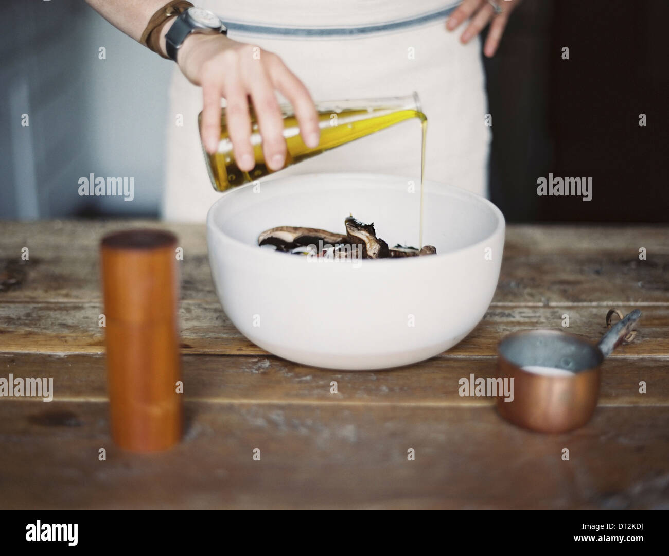 Eine häusliche Küche A Frau trägt eine Schürze, einen frischen Salat Gemüse in einer Schüssel mit Öl dressing Stockfoto