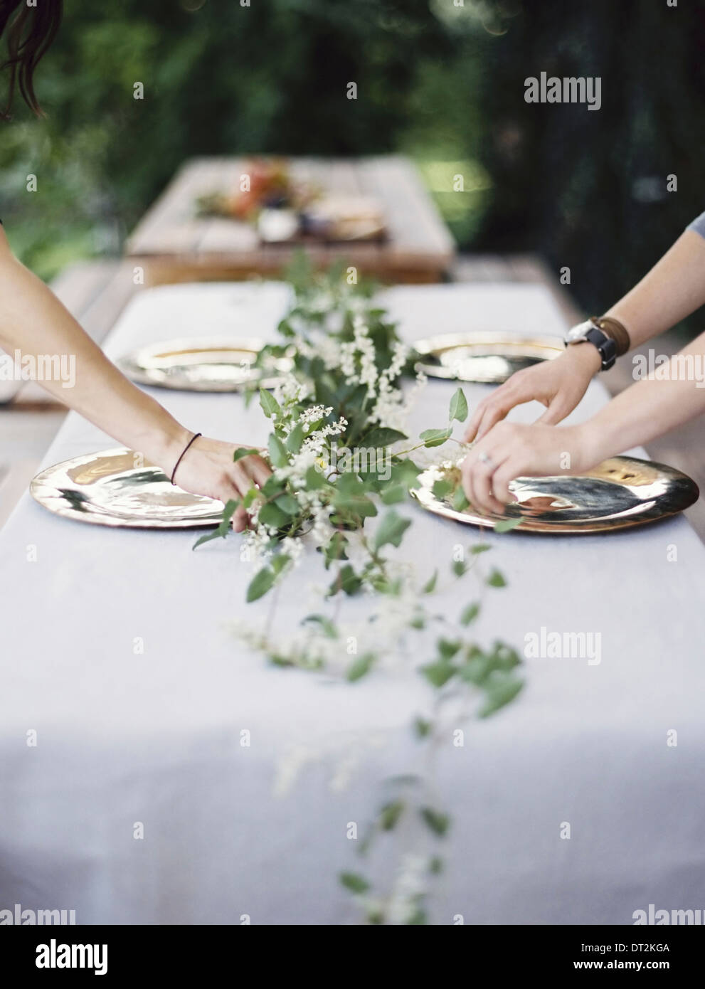 Zwei Personen, beugte sich über einen Tisch gelegt außerhalb mit einem weißen Tuch und eine zentrale Laub Tischdekoration Stockfoto