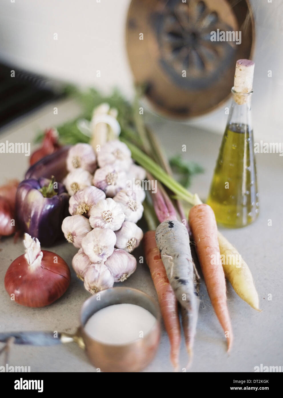 Eine Tischplatte A Gruppe von frischem Bio-Gemüse Karotten und Zwiebeln Knoblauch und Paprika A Flasche mit Öl und Kupfer Pfanne Sauce Stockfoto