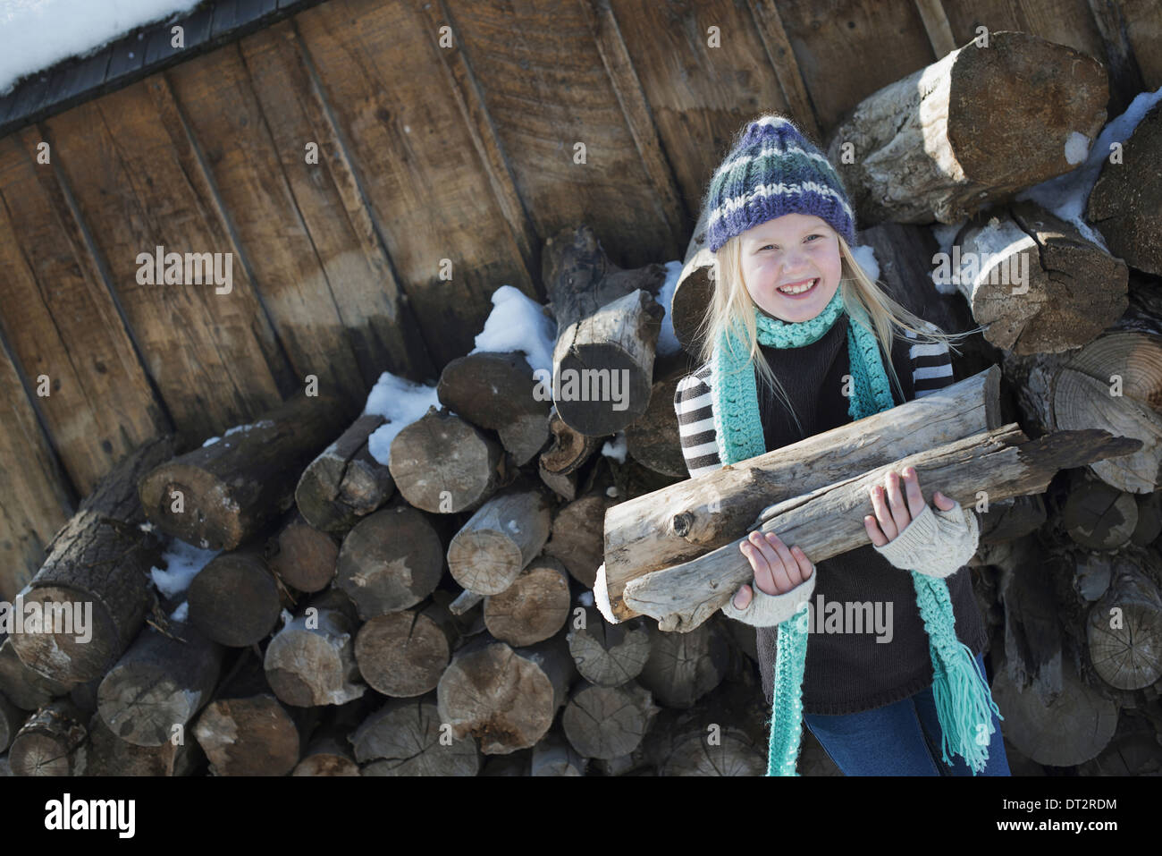 Winterlandschaft mit Schnee auf dem Boden ein Mädchen sammeln von Brennholz aus dem Protokoll-Stapel Stockfoto