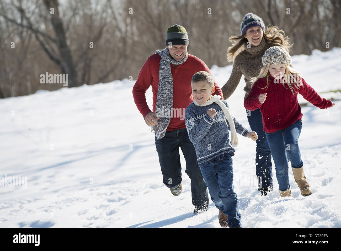 Winterlandschaft mit Schnee auf dem Boden Familie gehen zwei Erwachsene, zwei Kinder jagen Stockfoto