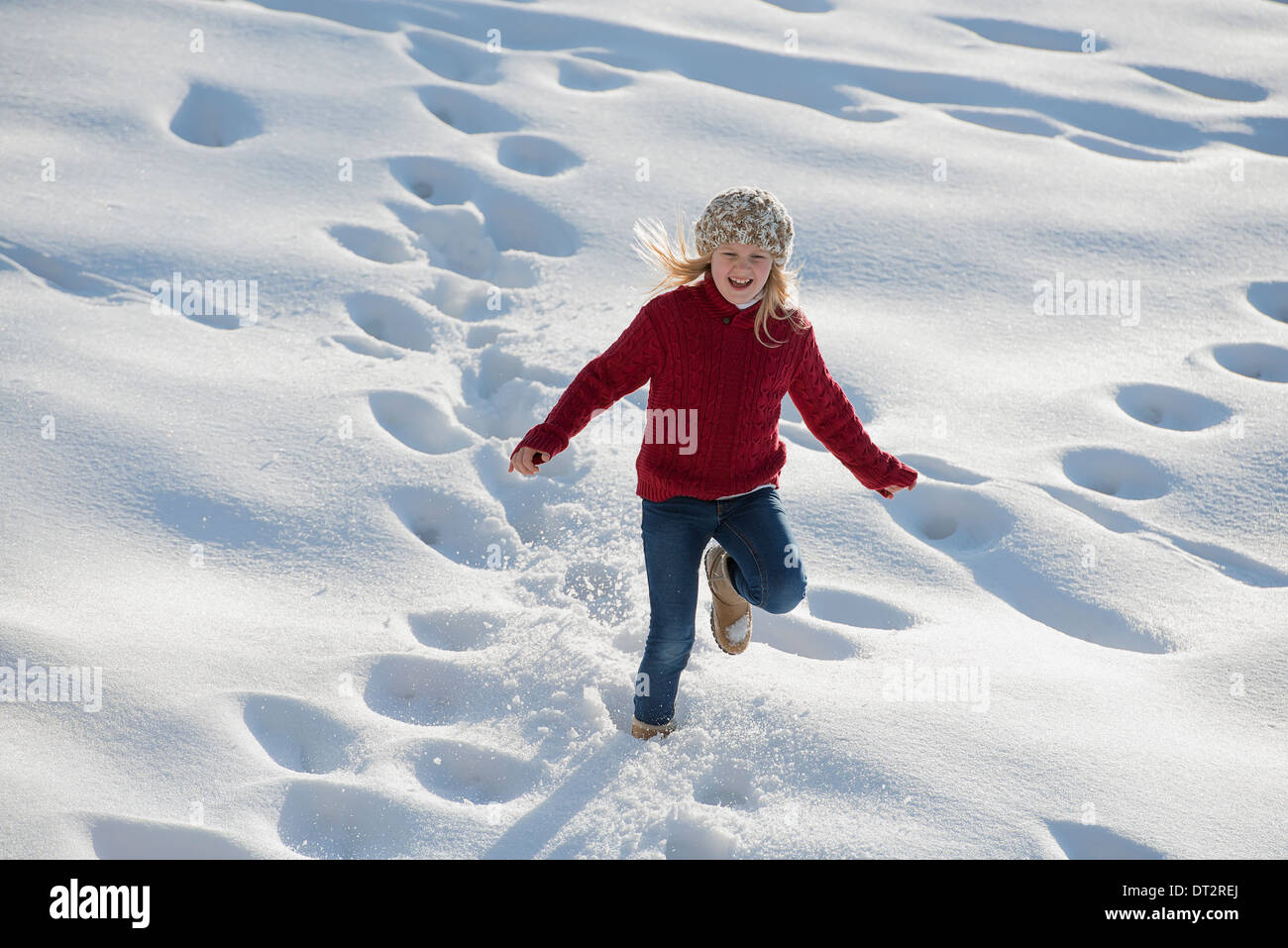 Winterlandschaft mit Schnee am Boden ein junges Mädchen läuft durch den Tiefschnee Fußabdruck Spuren Stockfoto