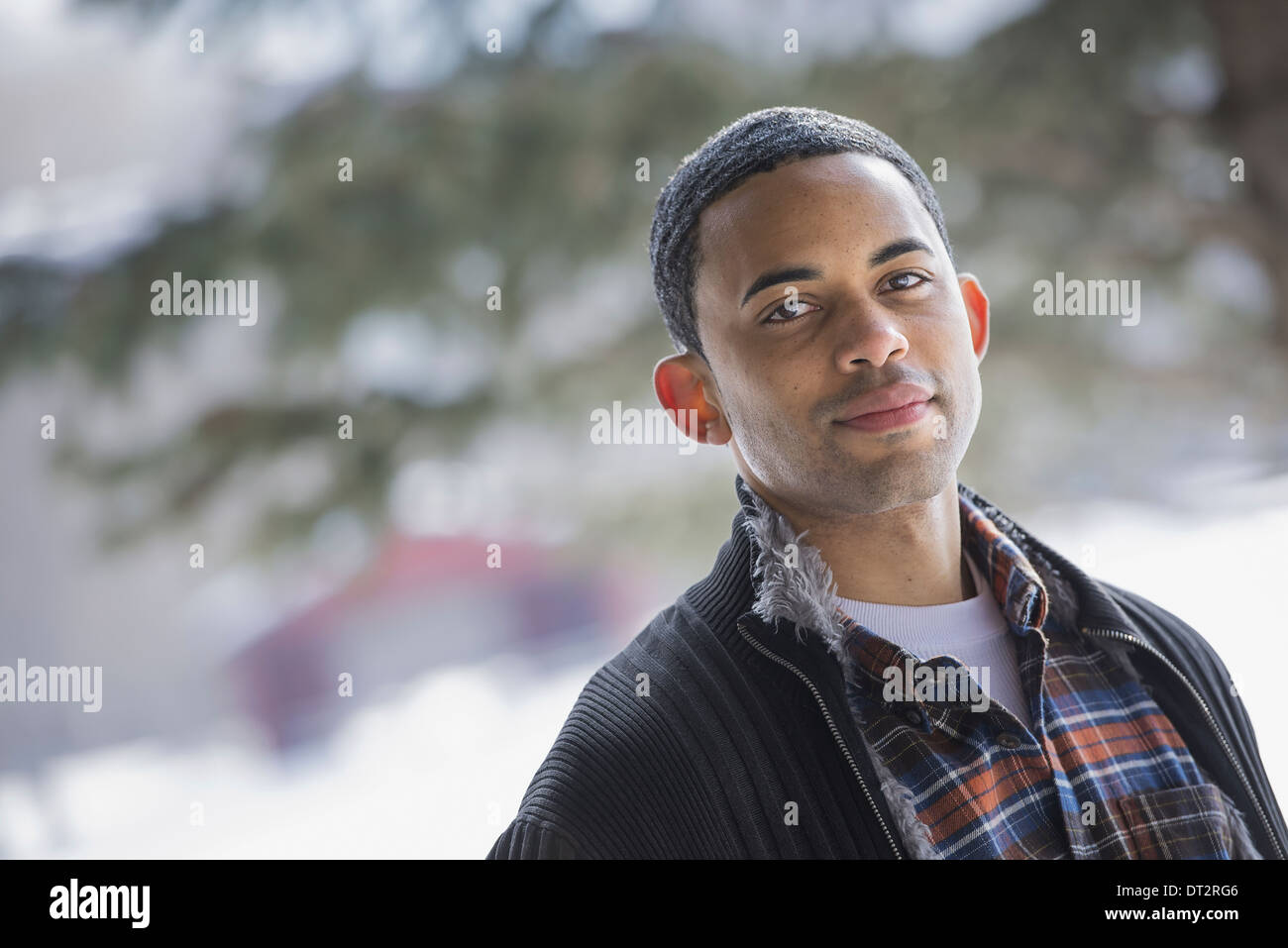 Winterlandschaft mit Schnee auf dem Boden A Mann trägt ein kariertes Hemd und offene Jacke Stockfoto