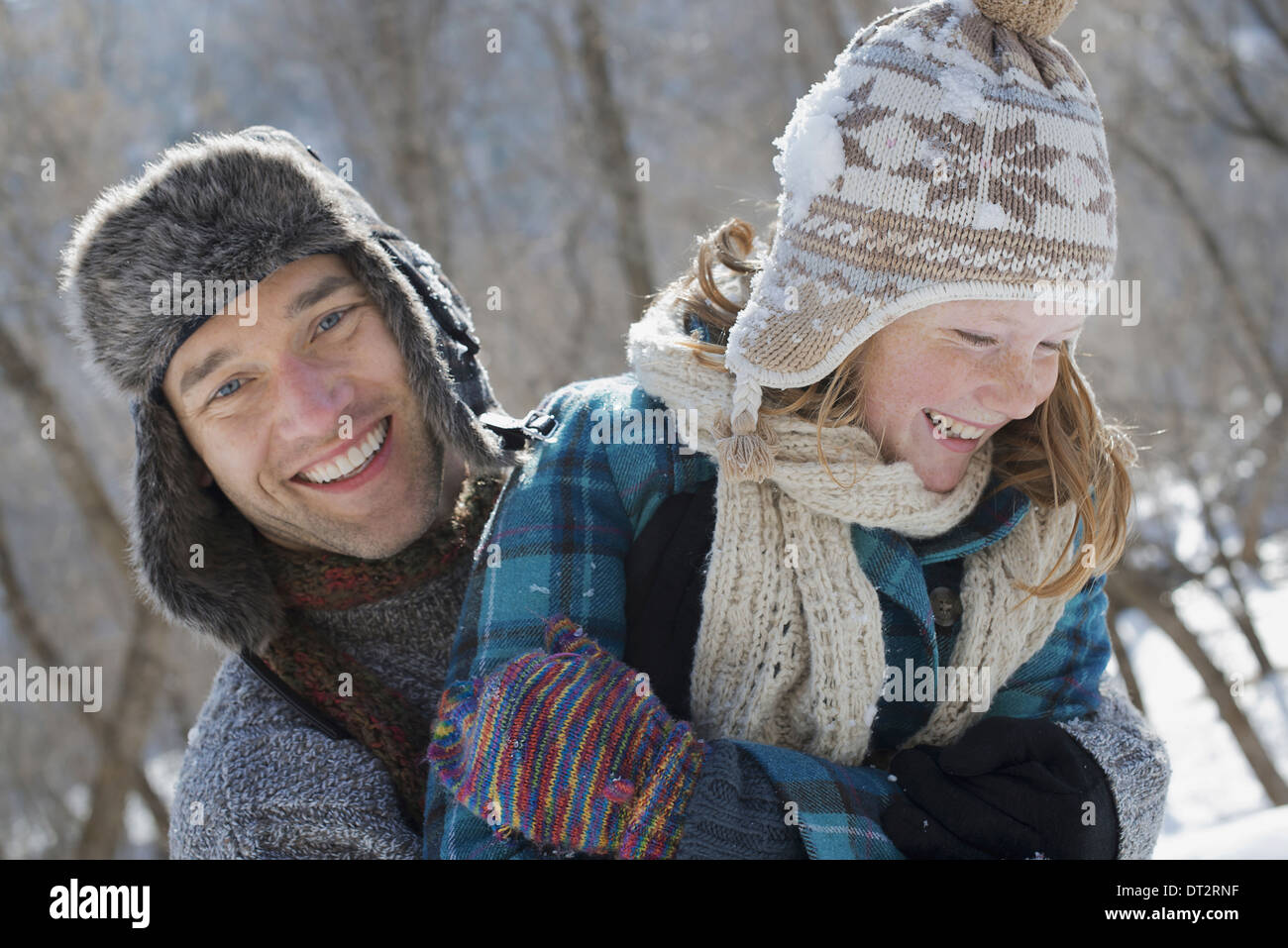 Winterlandschaft mit Schnee auf dem Boden A Woman with eine Pudelmütze und Schal und ein Mann umarmt Ihr Stockfoto