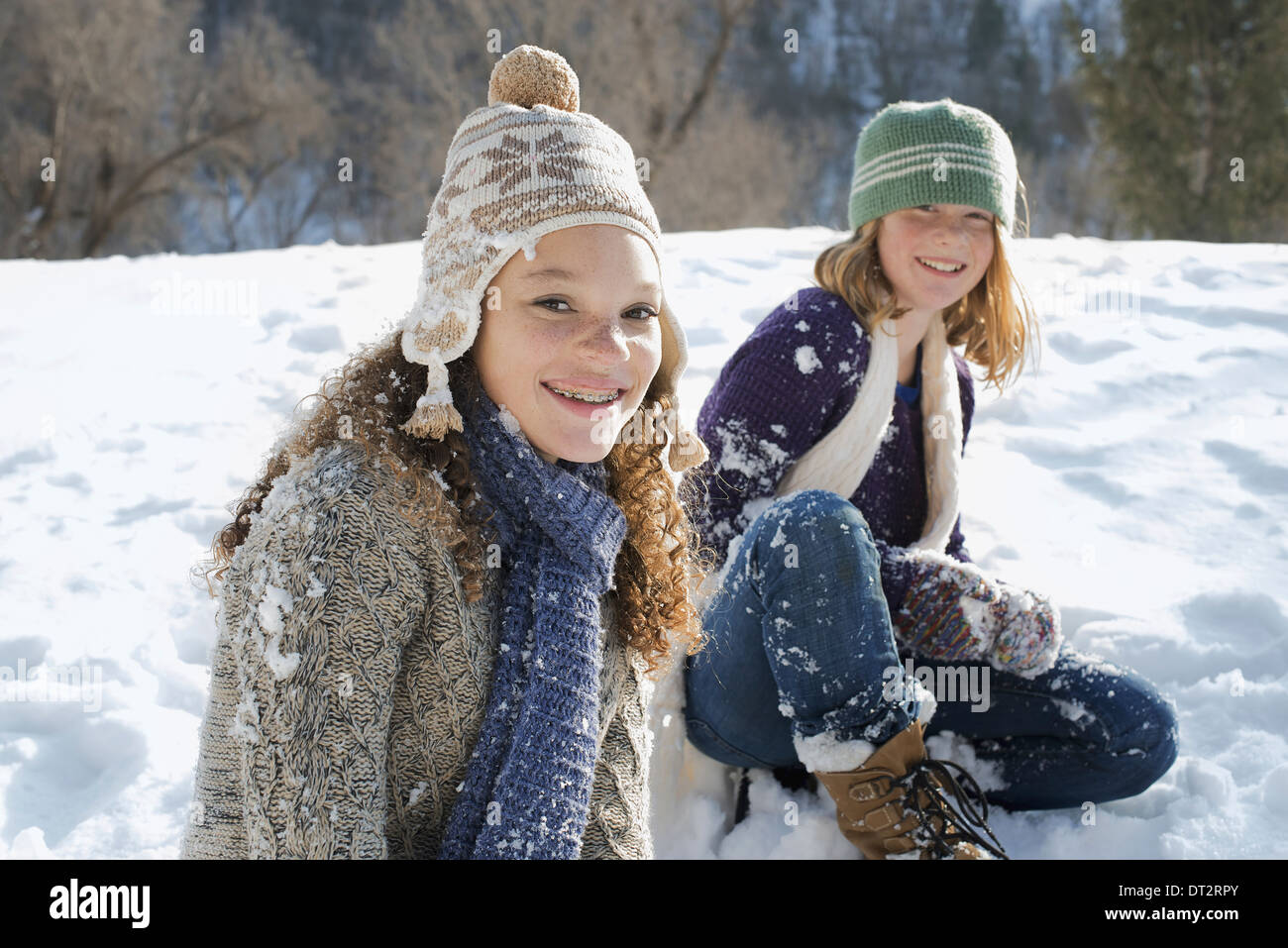 Winterlandschaft mit Schnee auf dem Boden A Frau und ein Kind sitzen auf dem Boden vor Lachen Stockfoto