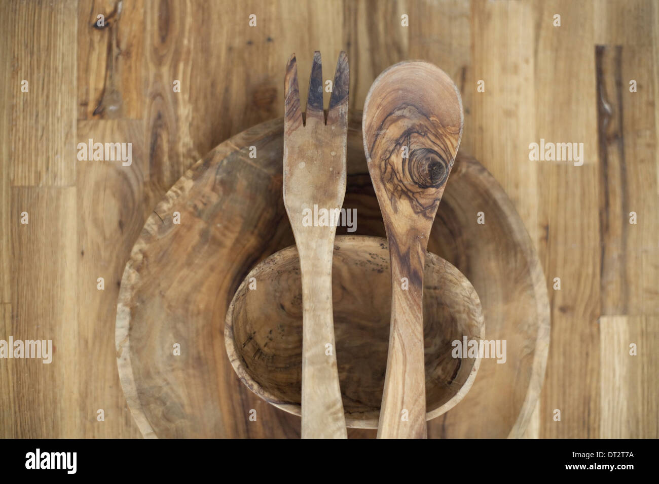 Eine hölzerne Tischplatte mit zwei gedrehten Schälchen und zwei hölzerne Salat Server Holzmaserung und natürlichen Muster Stockfoto