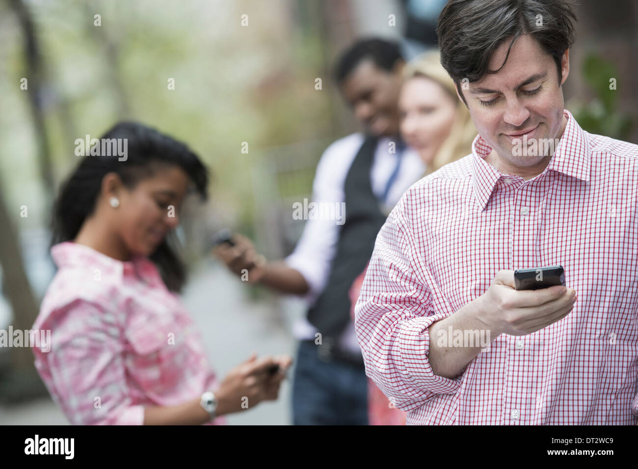 Blick über CityYoung Menschen im Freien in einem Park drei Stadtmenschen Überprüfung blickte auf ihre Handys Stockfoto