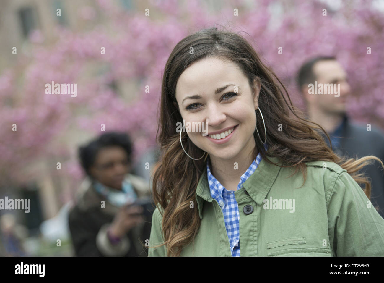 Kirschblütenbäume im Park eine junge Frau in einem offenen necked Hemd lächelnd und in die Kamera schaut Stockfoto