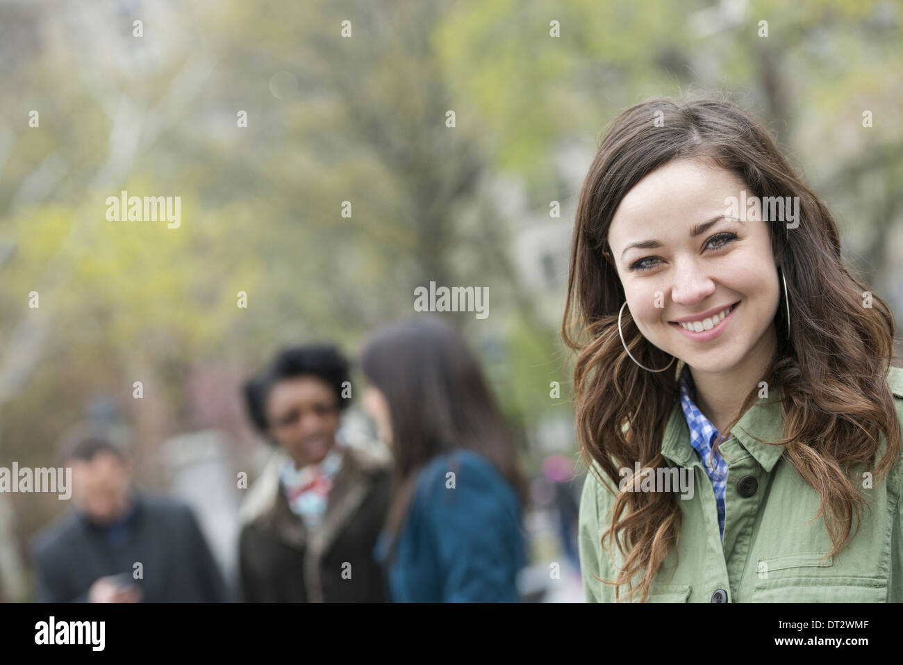 Eine Gruppe von Menschen im Park eine junge Frau in einem offenen necked Hemd lächelnd und in die Kamera schaut Stockfoto
