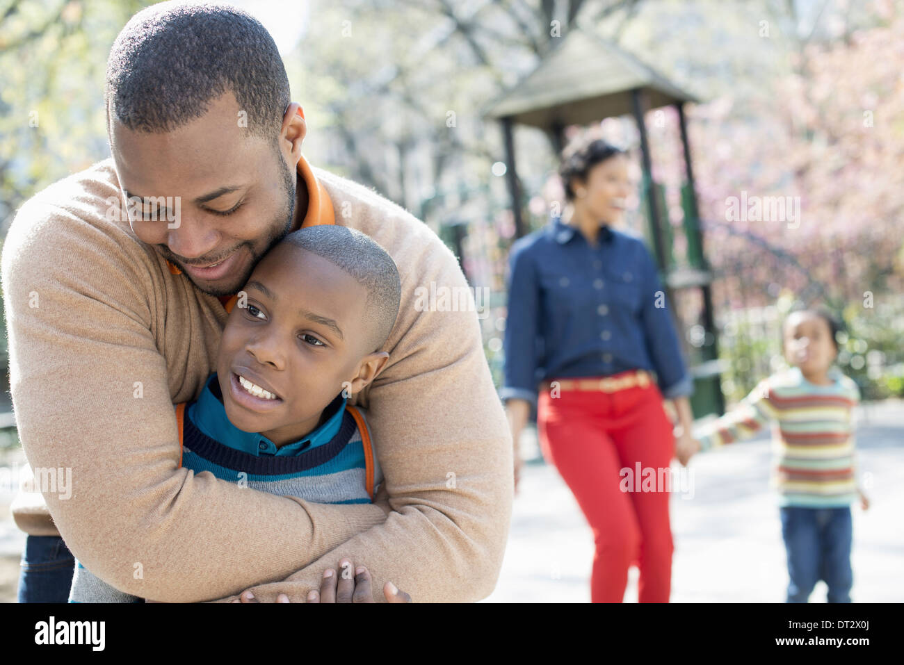 Eine Familie Eltern und zwei jungen, die gemeinsame Zeit eines Vaters seinen Sohn umarmt Stockfoto