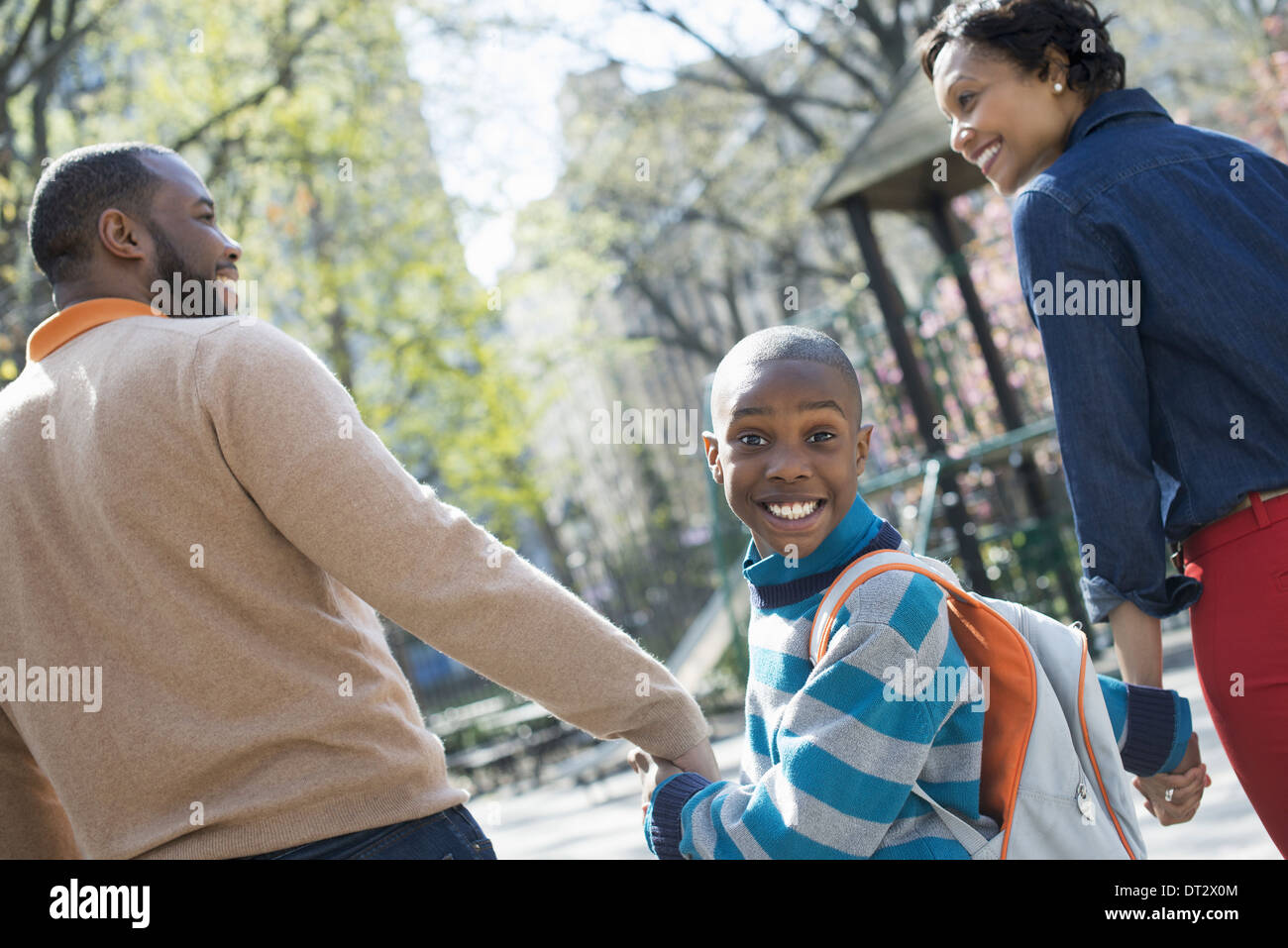 Sonnenschein und Cherry blossom ein Junge über seine Schulter zwischen seinen Eltern Stockfoto