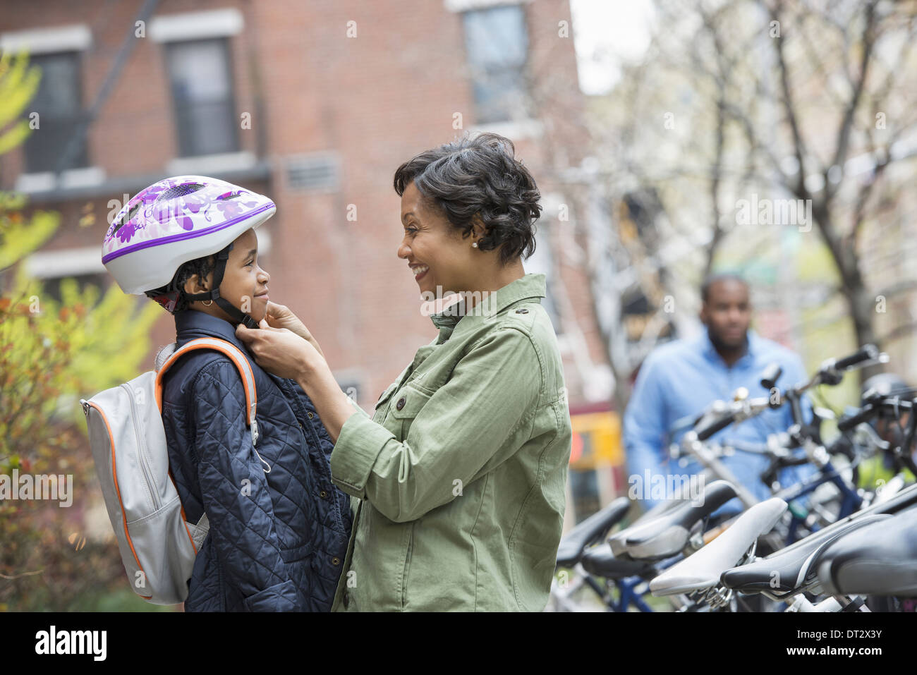 Ein Junge in eines Fahrradhelmes wird von seiner Mutter neben einen Fahrradträger befestigt Stockfoto