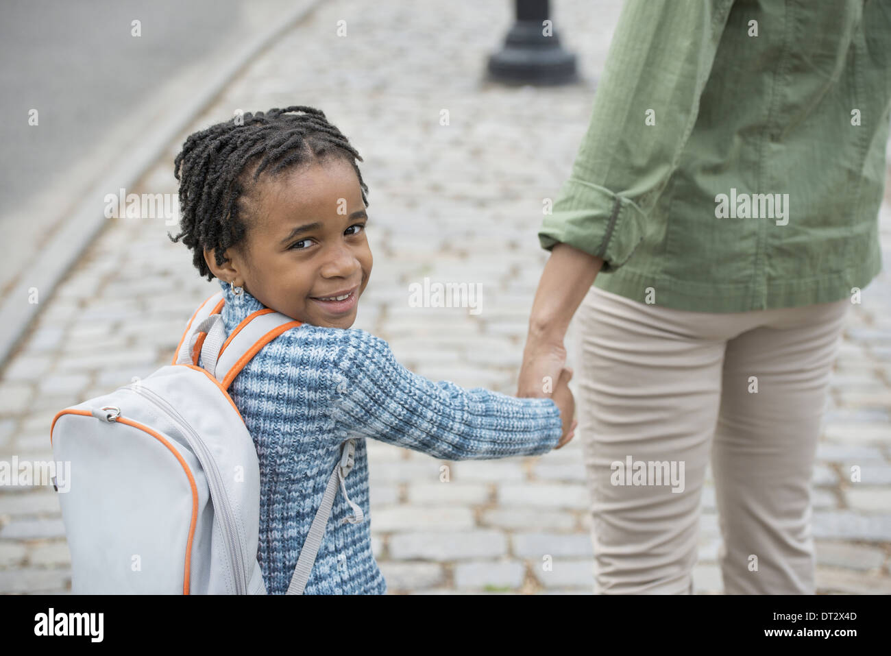 New York City Sonnenschein und Kirschen blühen ein Junge trägt eine Schule Schultasche und hand in hand gehen mit einer Frau Stockfoto