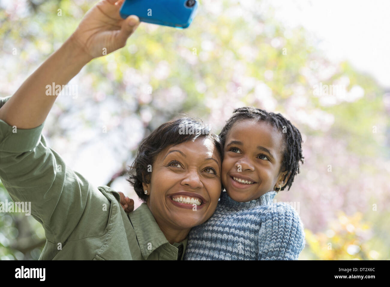 Sonnenschein und Kirschblüte A Mutter und Sohn posieren für ein Foto mit einem Smartphone Stockfoto