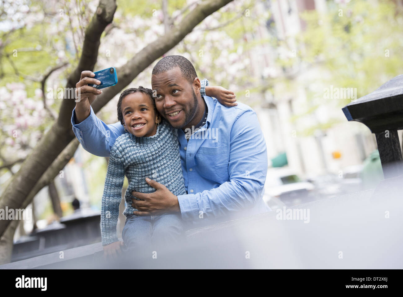 New York City Park Frühling Sonnenschein und Kirschblüte A Vater und Sohn Seite an Seite mit einem Smartphone zu fotografieren Stockfoto