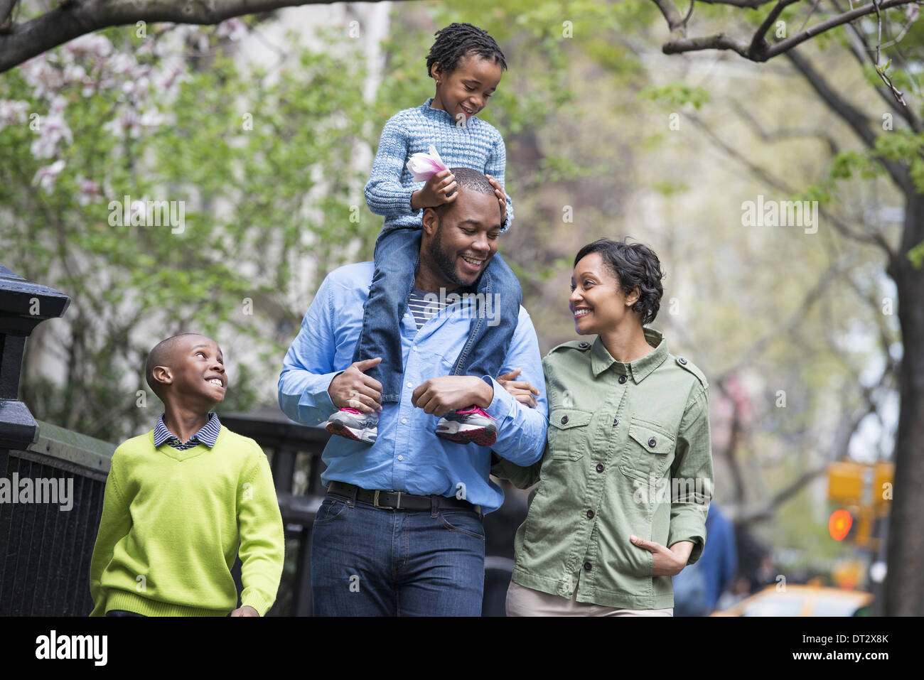 Eine Familie Eltern und zwei jungen A Child auf seines Vaters Schultern Reiten Stockfoto