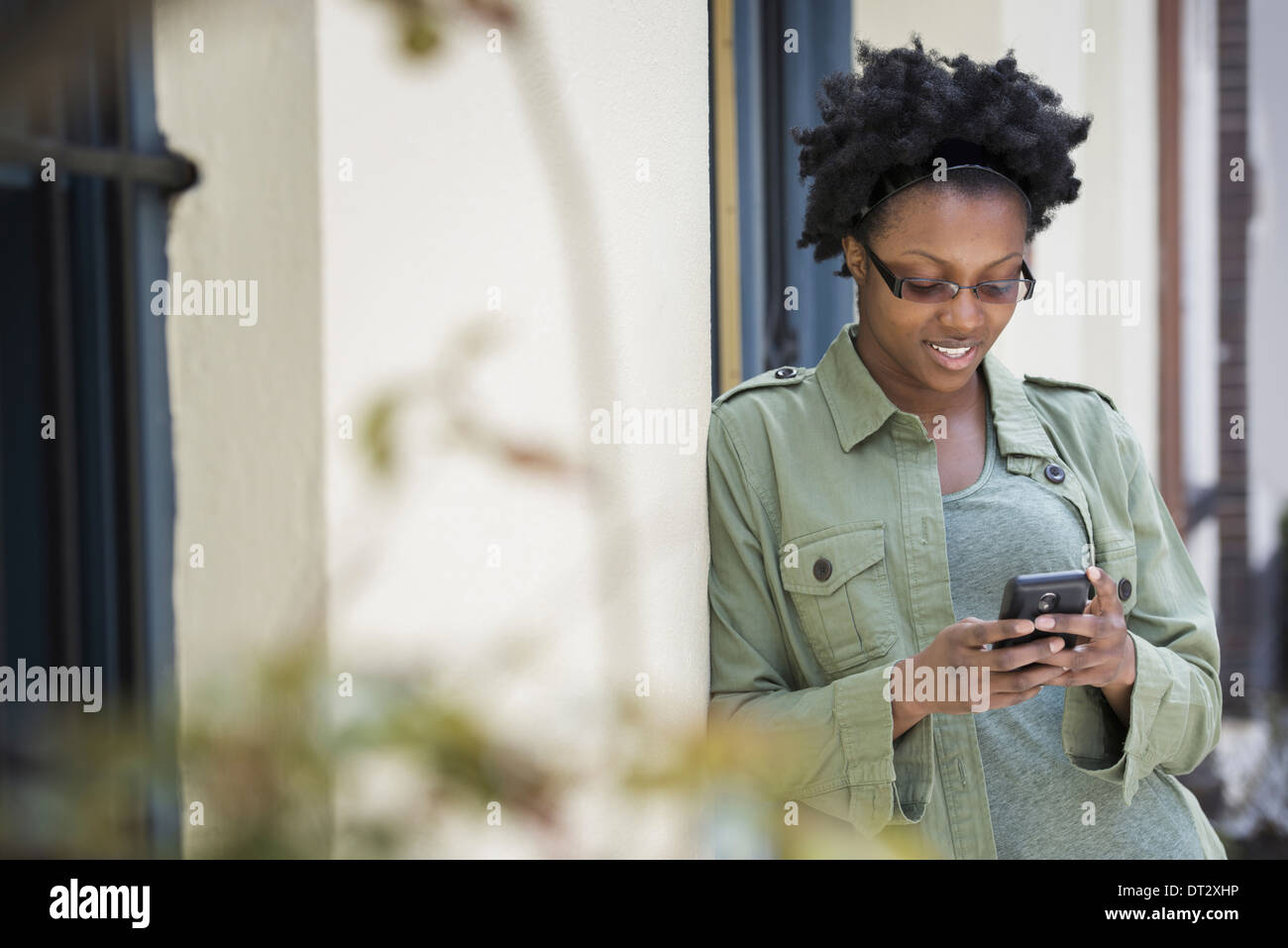 Eine Frau lehnte sich gegen einen Türrahmen überprüft ihr Telefon Stockfoto