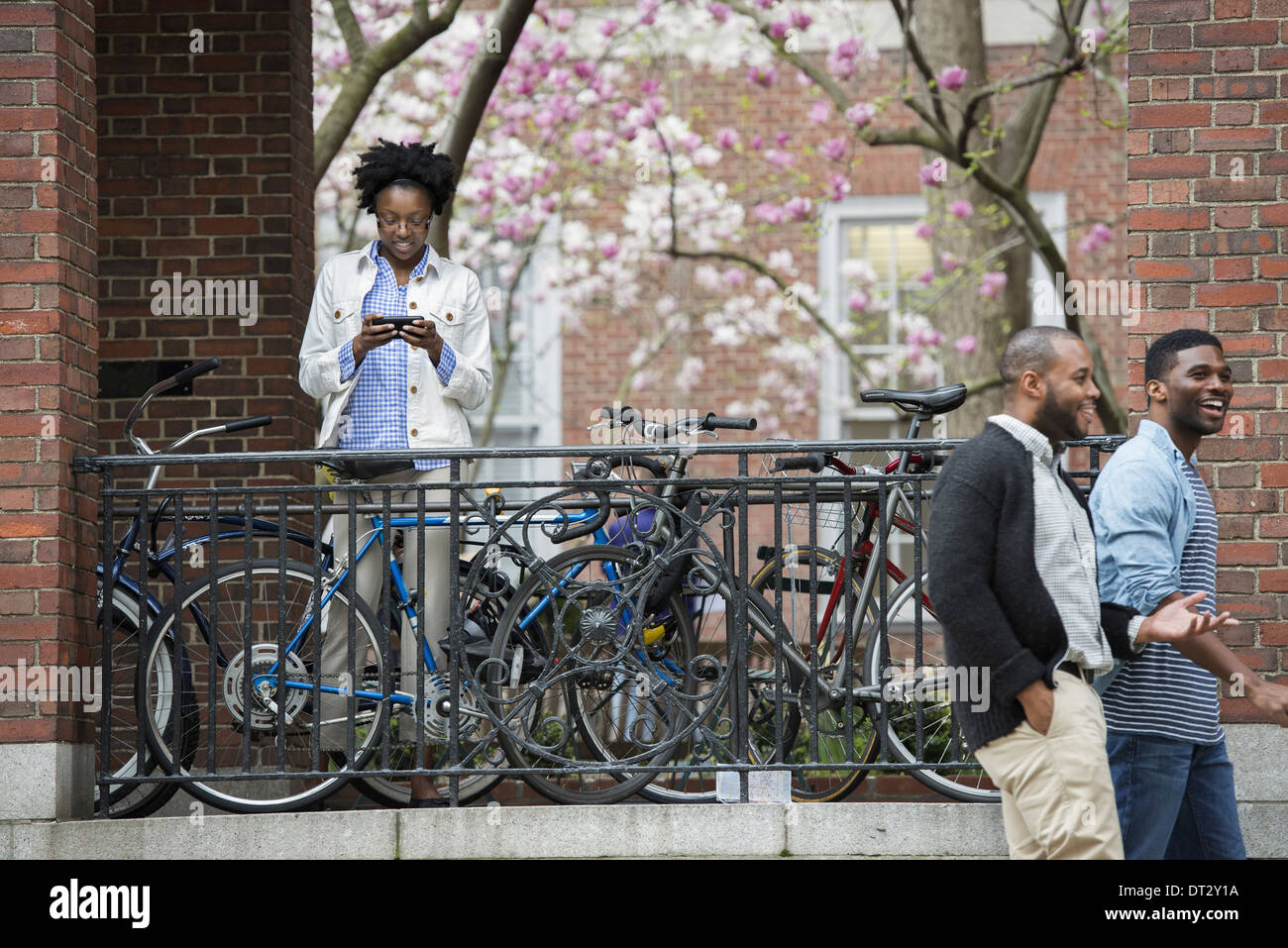 Ein Fahrrad rack mit gesperrten Fahrräder SMS eine Frau und zwei Männer zu Fuß durch Stockfoto