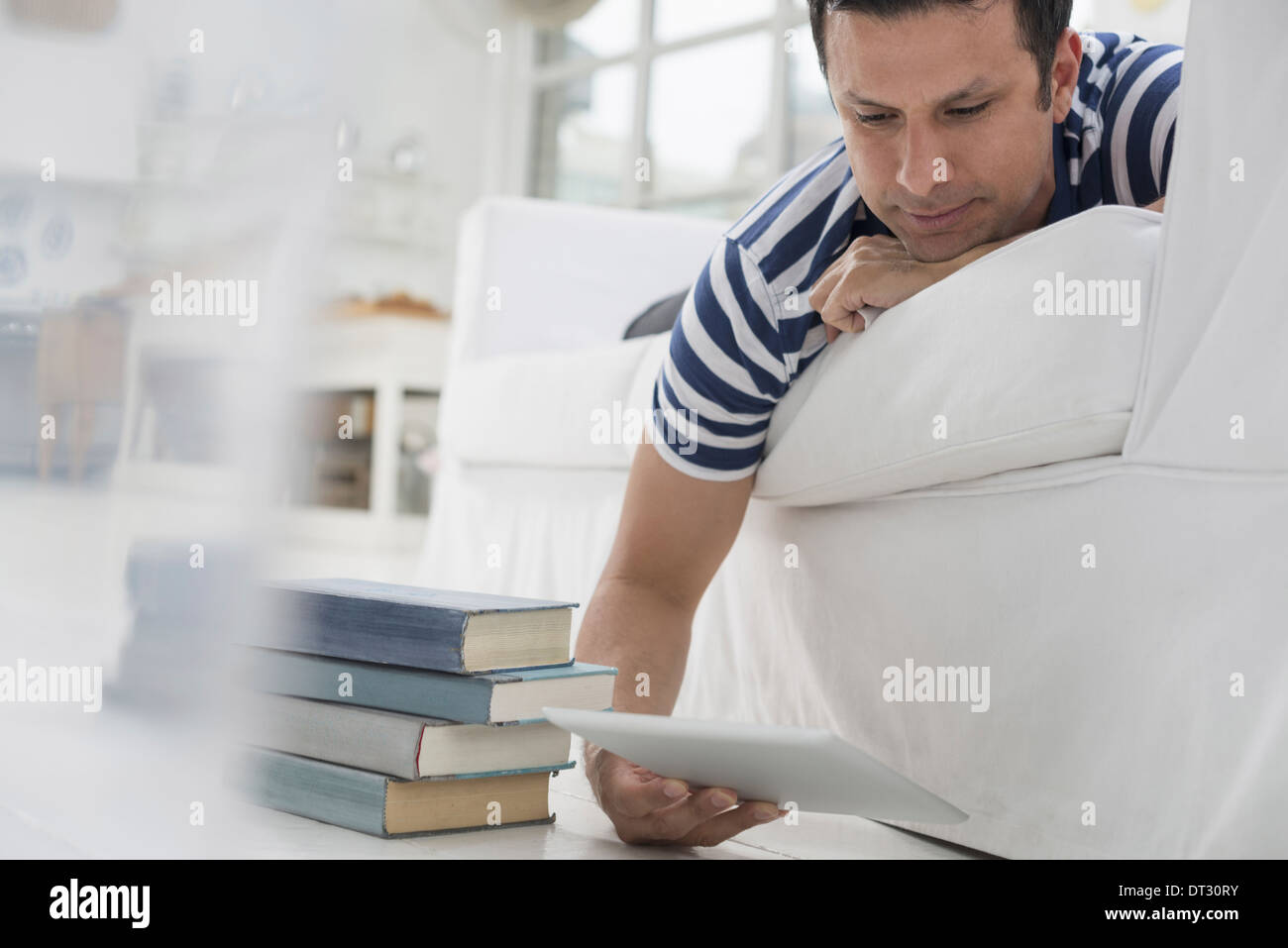 Mann liegt auf seiner Vorderseite auf einem Sofa in einer ruhigen luftig Büroumgebung mit einem digitalen tablet Stockfoto