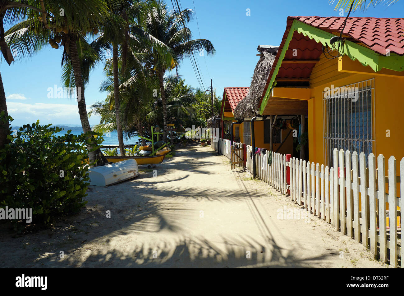 Sandigen Pfad entlang des Meeres mit Schatten der Kokospalmen und Urlaub Bungalows, Carenero Karibikinsel, Panama Stockfoto