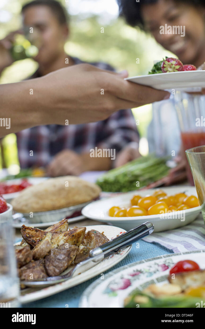 Ein Familien-Picknick in einem schattigen Waldgebiet Erwachsene und Kinder an einem Tisch sitzen Stockfoto