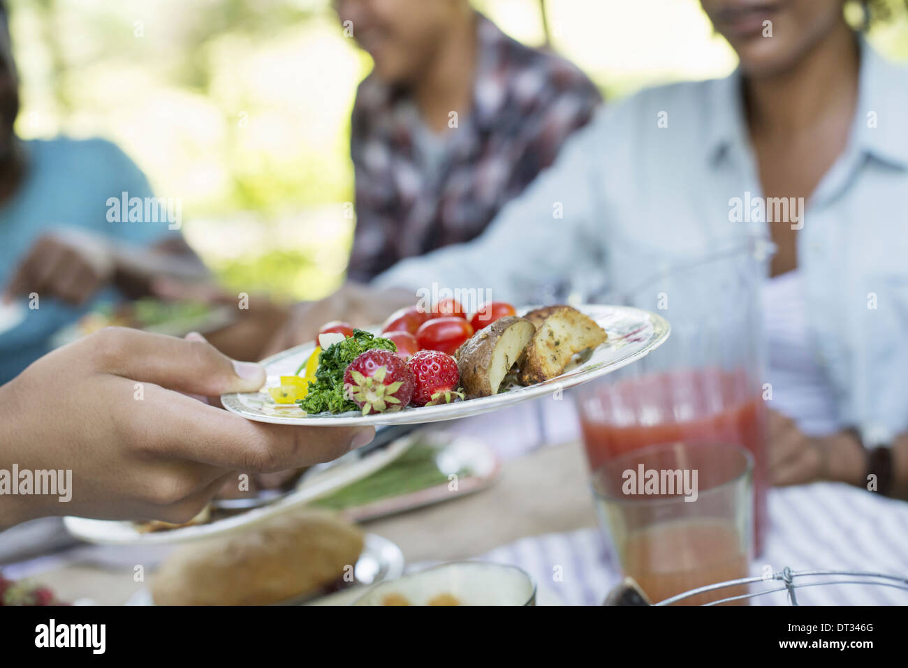 Ein Familien-Picknick in einem schattigen Waldgebiet Erwachsene und Kinder an einem Tisch sitzen Stockfoto