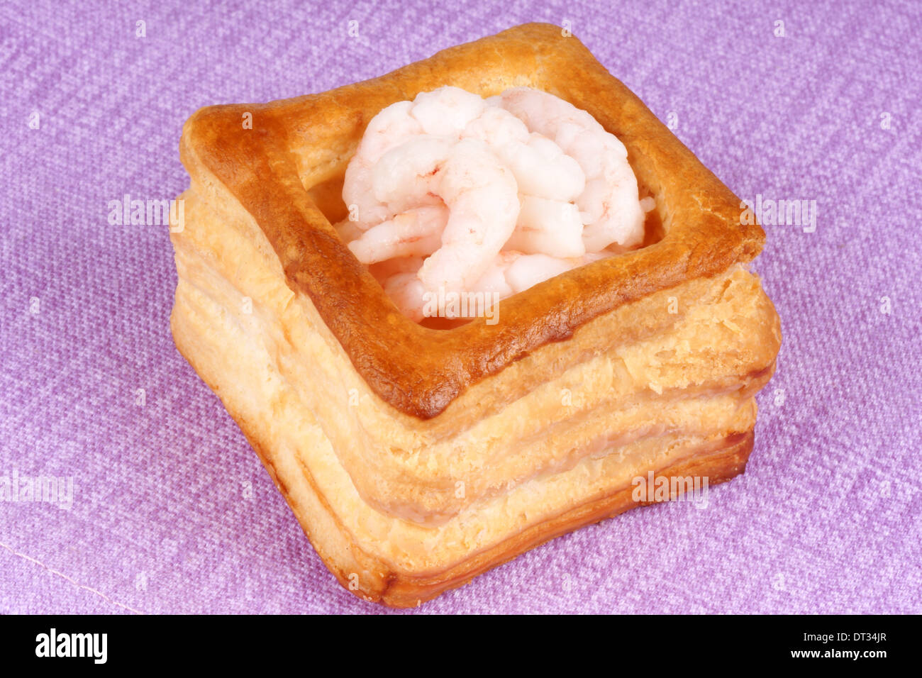 Nahaufnahme einer Blätterteigpastete mit kleinen gekochte Garnelen auf einem rosa Stoff-Hintergrund. Stockfoto