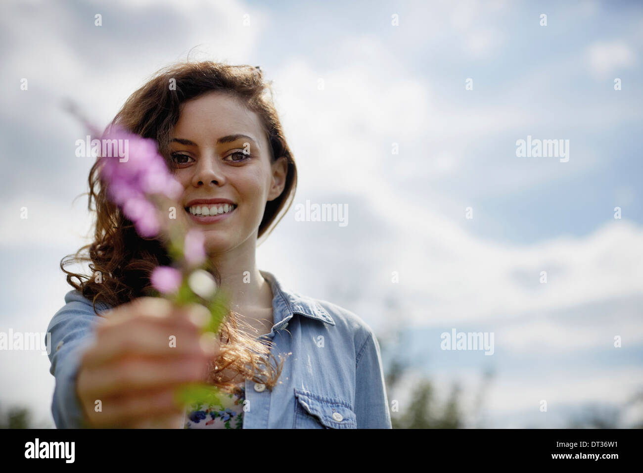 Eine junge Frau in der Hand aus einer wilden Blume mit rosa Blüten Stockfoto
