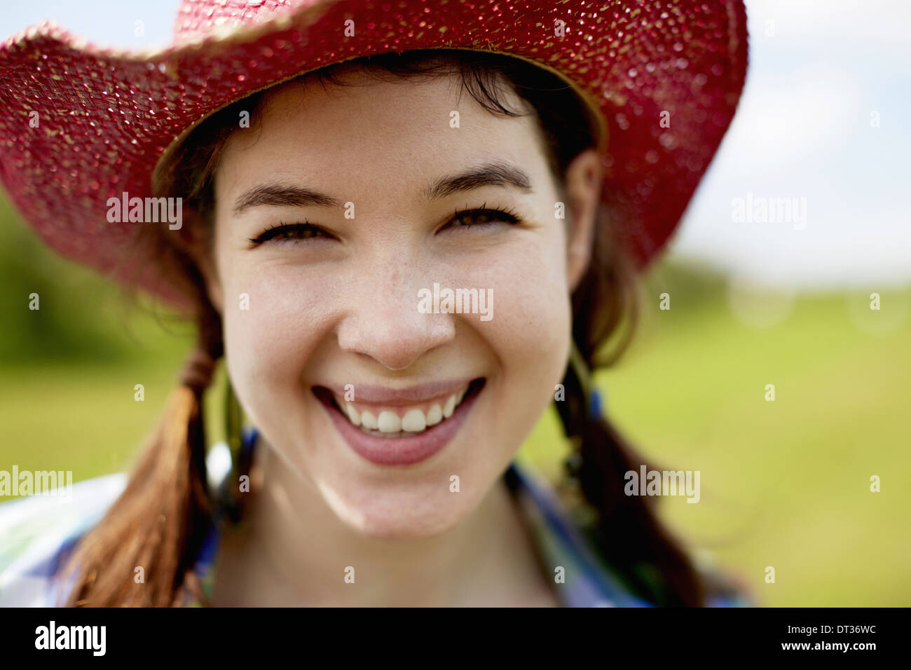 Eine junge Frau in einem rosa Strohhut lächelt breit Stockfoto