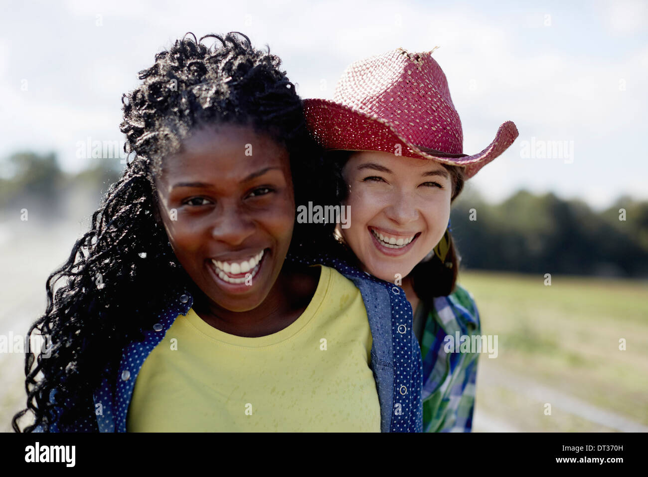 Zwei junge Frauen, die zusammen mit einer Sprinkleranlage im Hintergrund stehend Stockfoto