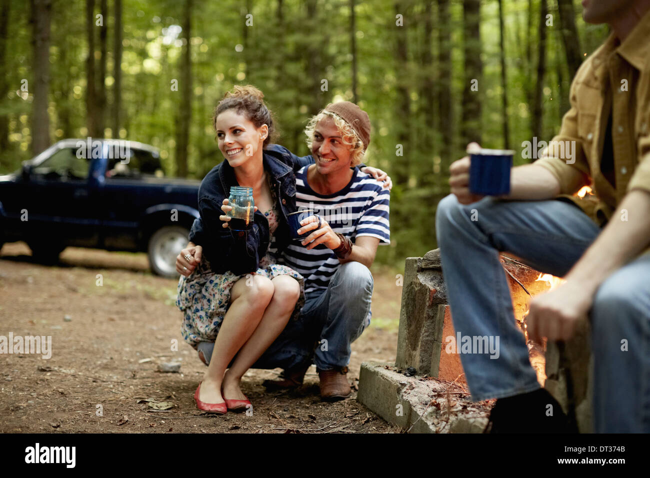 Drei Personen sitzen um ein Lagerfeuer in der Dämmerung Stockfoto