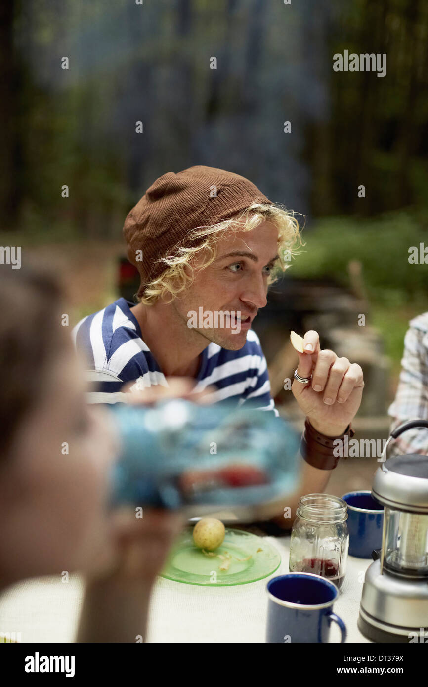 Ein junger Mann sitzt an einem Picknicktisch im Wald Stockfoto