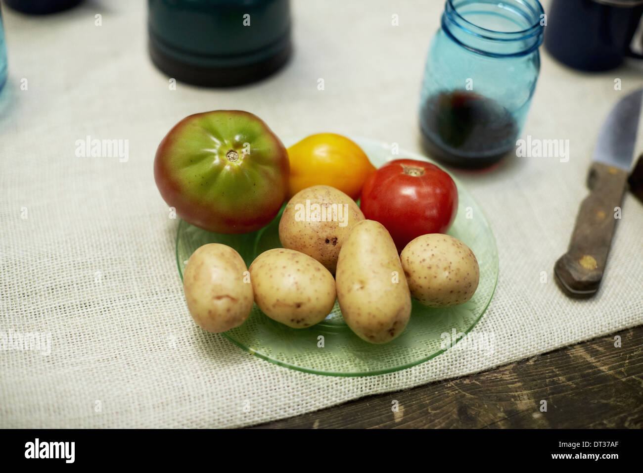Eine Tabelle mit einem Tuch und Teller mit Kartoffeln und Tomaten Stockfoto