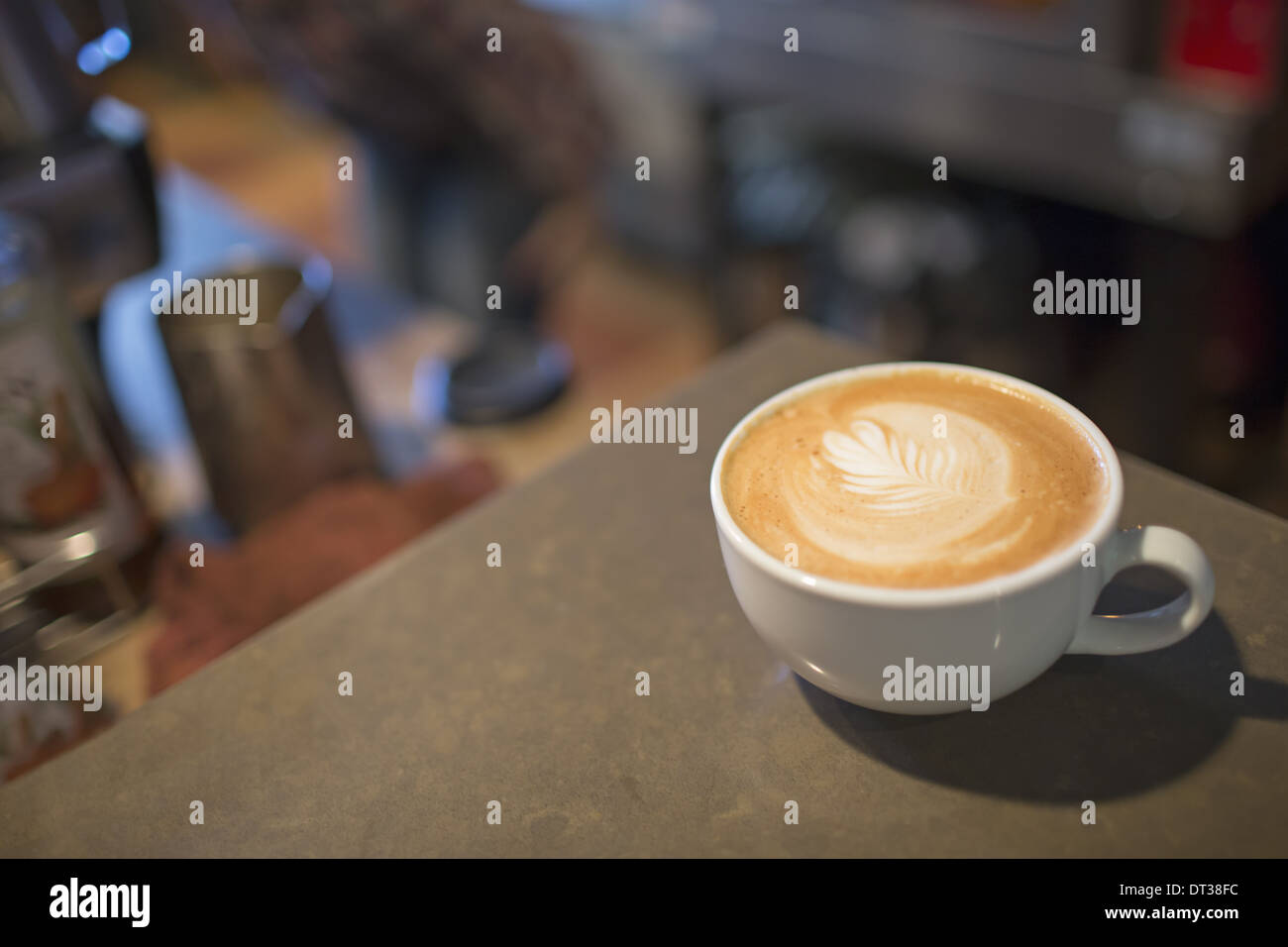 Café-Tisch. Eine weiße China Tasse Kaffee mit aufgeschäumter Milch. Stockfoto