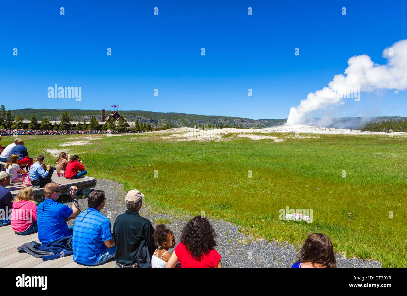 Touristen, die beobachtete Ausbruch des Old Faithful Geysir Old Faithful Inn im Hintergrund, Yellowstone-Nationalpark, Wyoming, USA Stockfoto