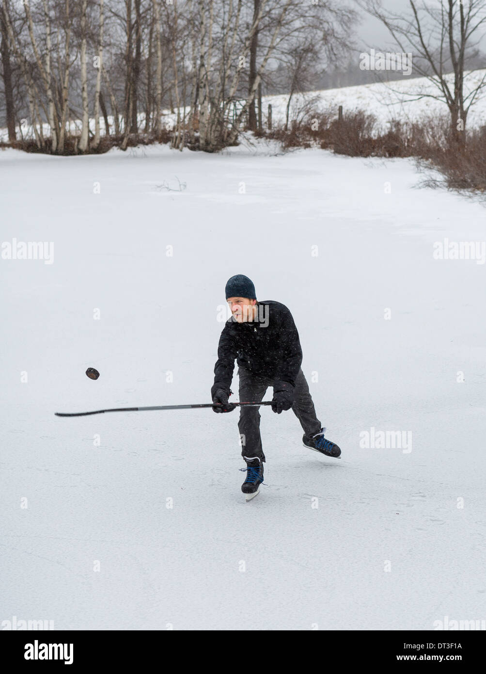 WARREN, VERMONT, USA - Mann Schlittschuhlaufen auf zugefrorenen Teich, Hockeyspielen, Puck jonglieren. Stockfoto