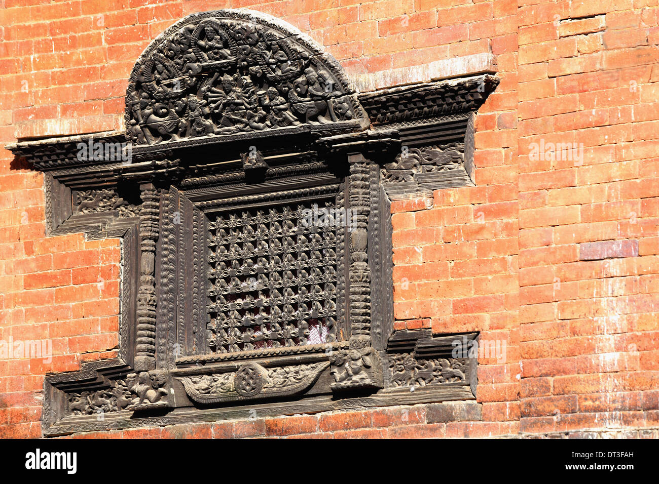 Dunkle geschnitzten hölzernen Gitter Fenster auf roten Backsteinmauer. Durbar Square-Patan-Lalitp Ihr Bezirk-Nepal. 0153 Stockfoto