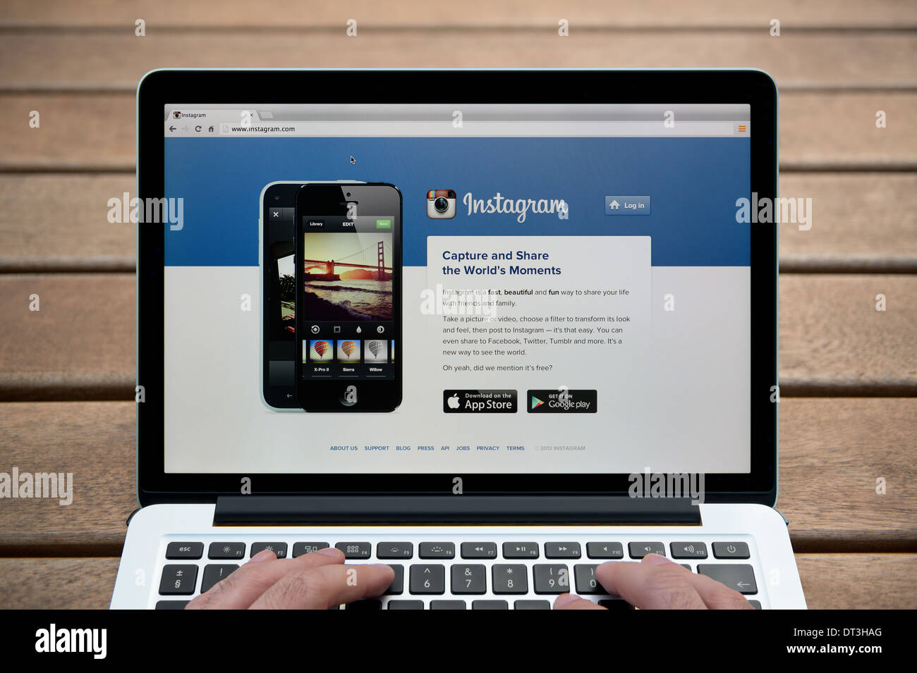 Der Instagram-Website auf einem MacBook Hintergrund eine Holzbank im Freien einschließlich eines Mannes Finger (nur zur redaktionellen Verwendung). Stockfoto