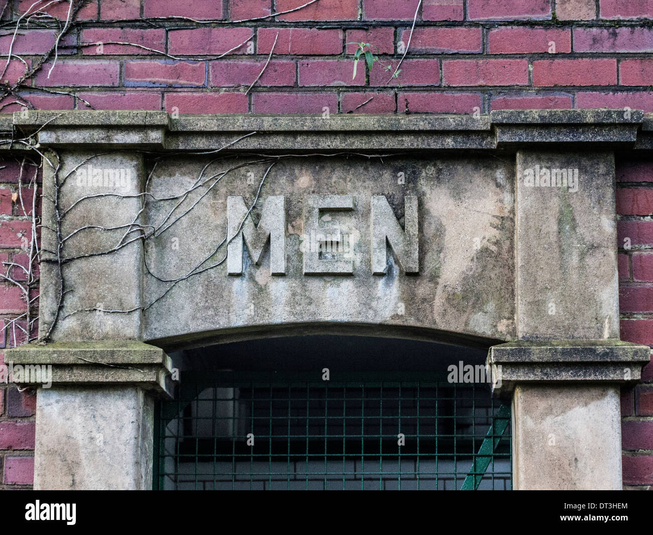 Stillgelegten Herren WC Tür Eingang an lokalen Park mit einem grünen Netz Zaun Stockfoto