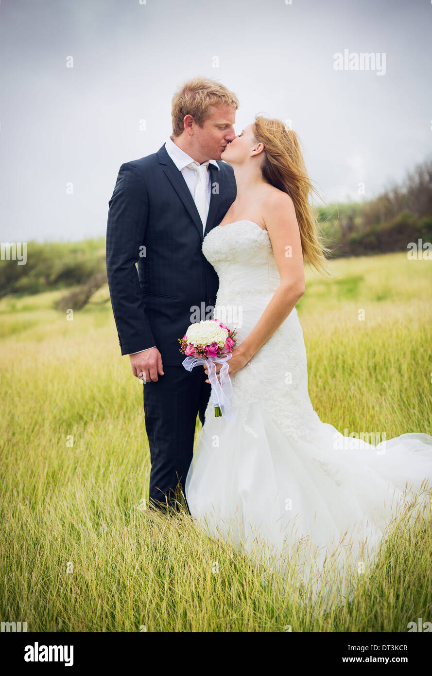Hochzeit paar, glücklich romantische Braut und Bräutigam verliebt küssen im Feld Stockfoto