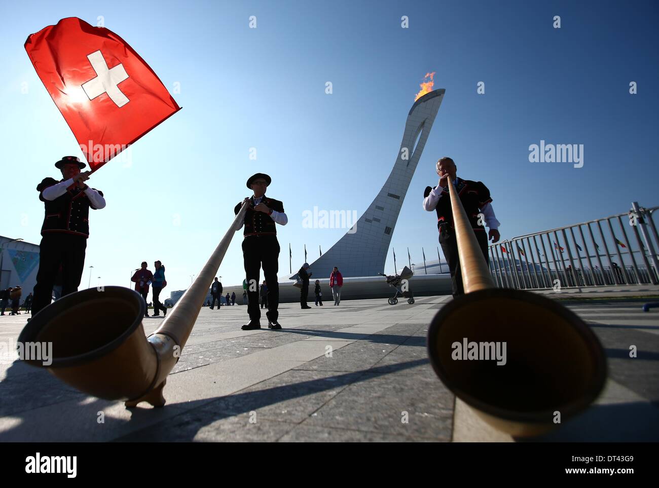 Sotschi, Russland. 8. Februar 2014. Schweizer Alphornbläser aus Engadin posieren vor das Olympische Feuer im Olympiapark bei Sotschi 2014 Olympischen Spielen in Sotschi, Russland, 8. Februar 2014. Foto: Christian Charisius/Dpa/Alamy Live News Stockfoto