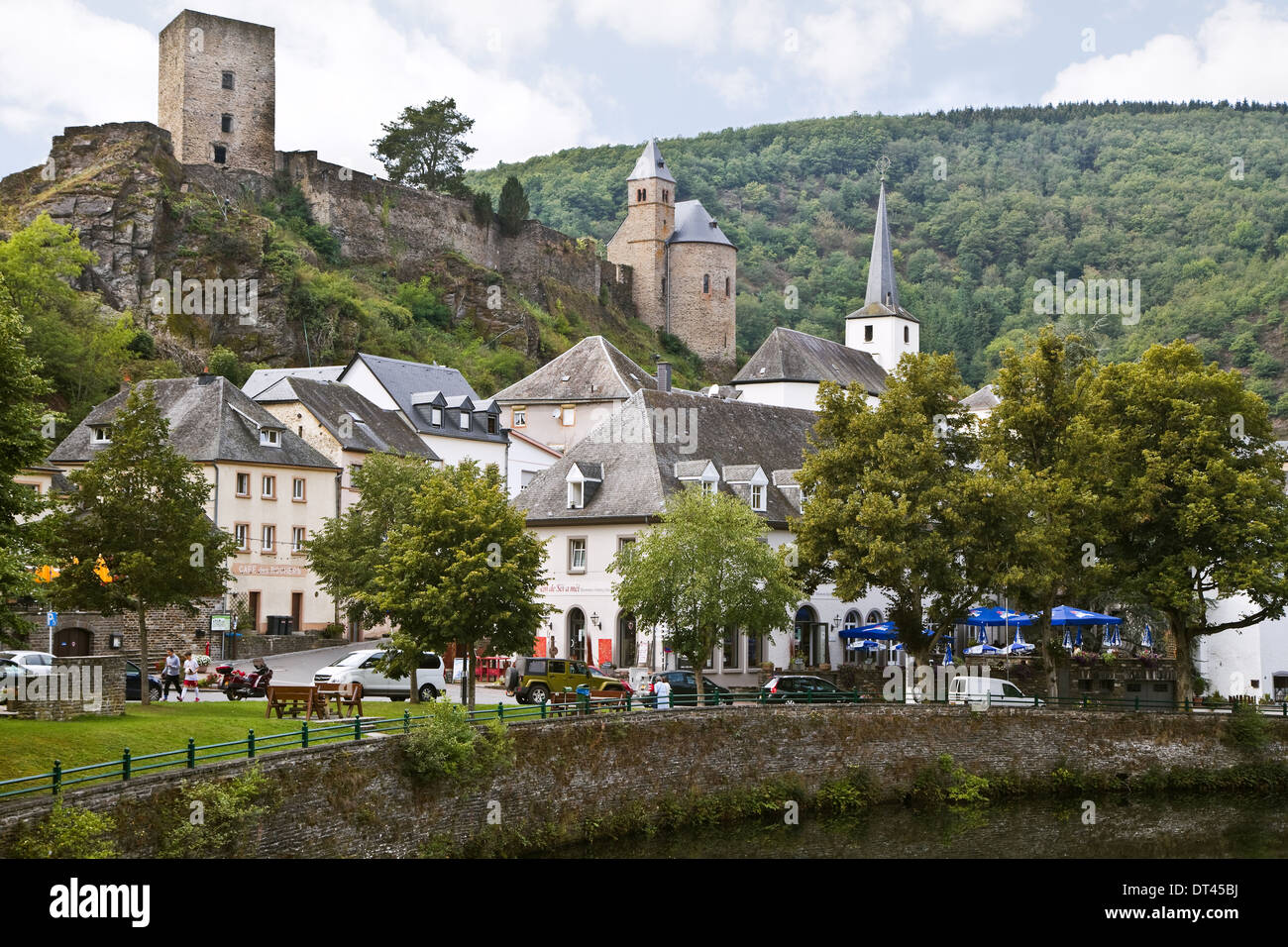 Blick auf Esch-sur-Sûre, Luxemburg, Europa an einem bewölkten Tag, wie man ihn im Sommer vom Flussufer aus sieht, mit Ruine einer alten Burg auf dem Hügel Stockfoto